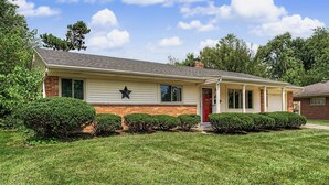 A single-story house with a red door, a star decoration on the wall, and a well-maintained lawn.