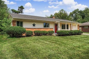 A single-story house with a red door, a star decoration on the wall, and a well-maintained lawn.
