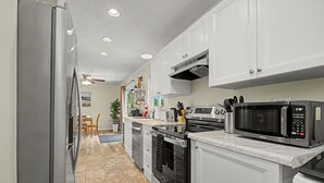 A kitchen with white cabinets, a microwave, an oven, and a refrigerator.