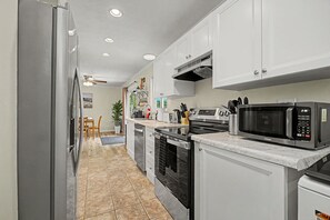A kitchen with white cabinets, a microwave, an oven, and a refrigerator.