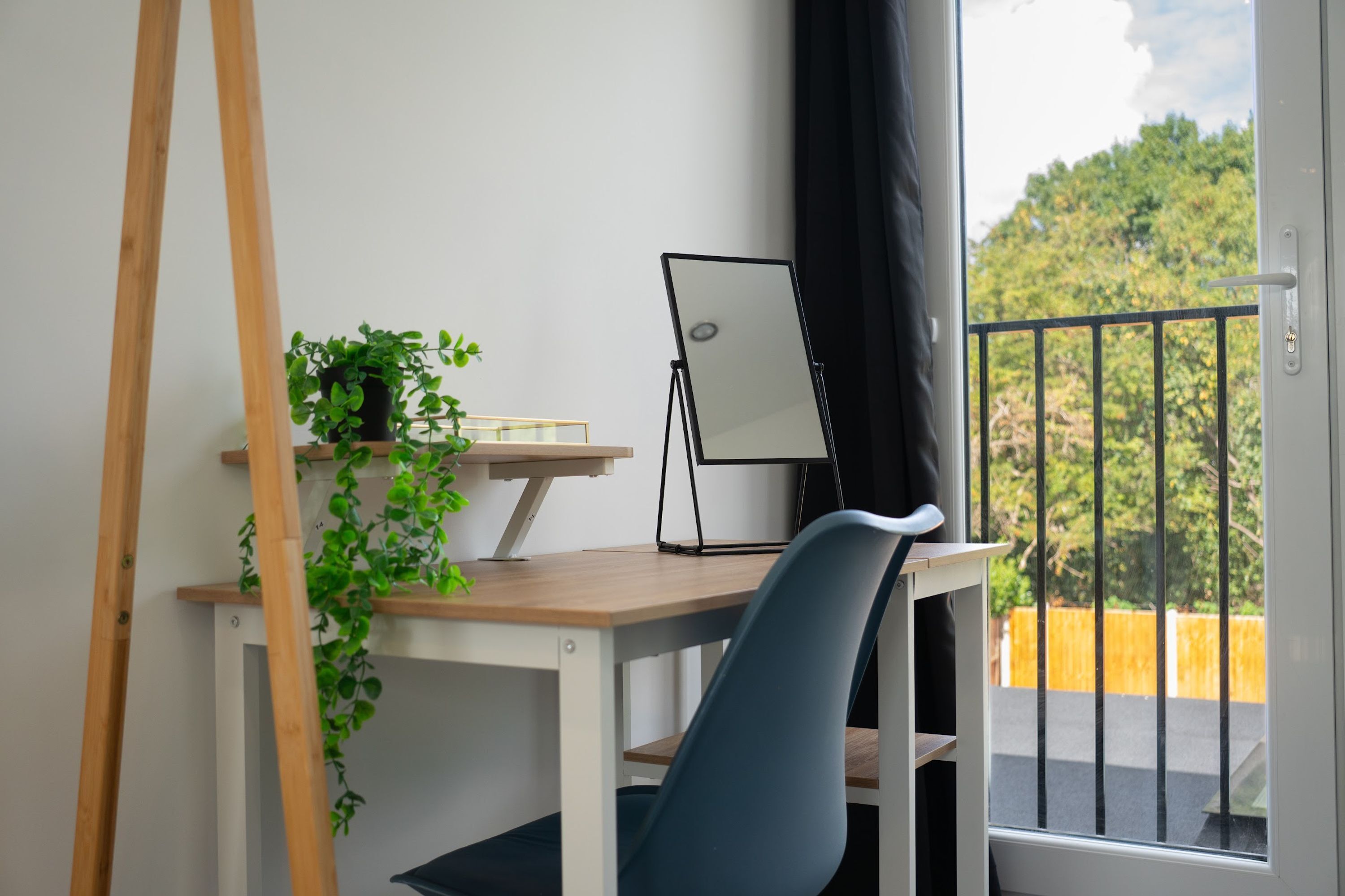A workspace with a desk, chair, easel, and potted plant.