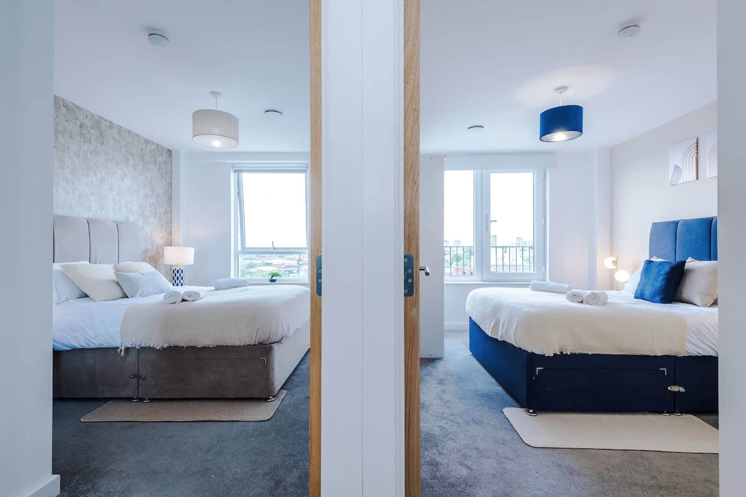 Une vue en coupe d’une chambre d’hôtel moderne, avec deux lits, de grandes fenêtres et une vue sur la ville.
