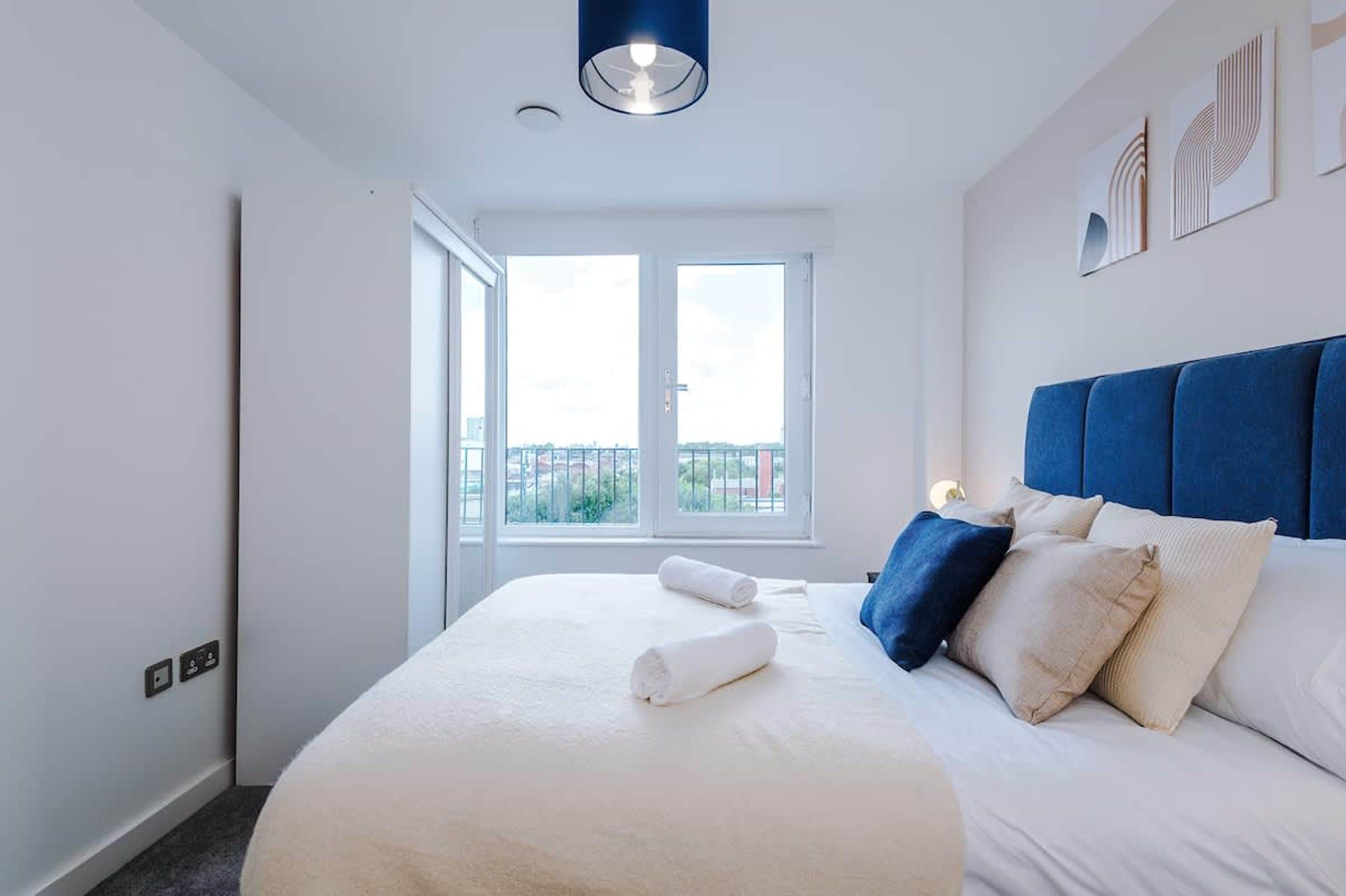 Una camera d'albergo con un letto grande, vista dalla finestra e un poggiatesta blu.