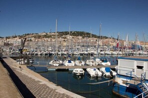 Ein Yachthafen mit mehreren vertäuten Booten, blauem Himmel und Gebäuden im Hintergrund.