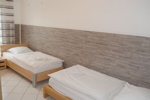 A hotel room with two single beds, a wooden headboard, and a tiled floor. - Strandpalais, Whg. 127 Penthouse (Cuxhaven)