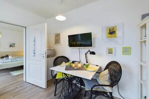 Een kamer met een bed, een bureau met stoel, een televisie en kunstwerken aan de wanden.