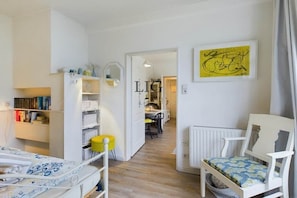 A child's bedroom with a crib, a bookshelf, and a chair. - Holiday apartment cockle (Langeoog)