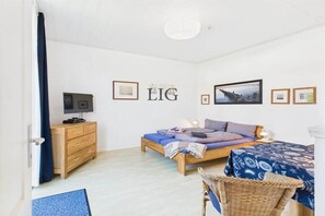 Ein Schlafzimmer mit einem Bett, einer Kommode, einem Fernseher und einem an der Wand hängenden Kunstwerk.