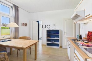 Eine moderne Küche mit einem Holztisch, einer eingebauten Schrankwand und einem Fenster mit Vorhängen.