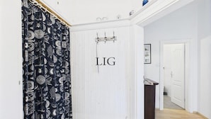 Un pasillo con una puerta blanca que tiene la etiqueta 'LIG' y una cortina estampada.