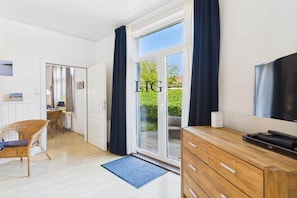 Een moderne woonkamer met een televisie, een houten kast en een schuifdeur naar een buitenruimte.