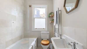 Un bagno con vasca, lavandino, water e finestra.