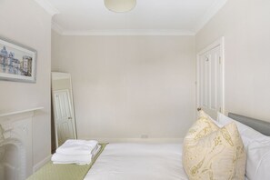 Een hotelkamer met een bed, een nachtkastje, een wandplank en een deur.