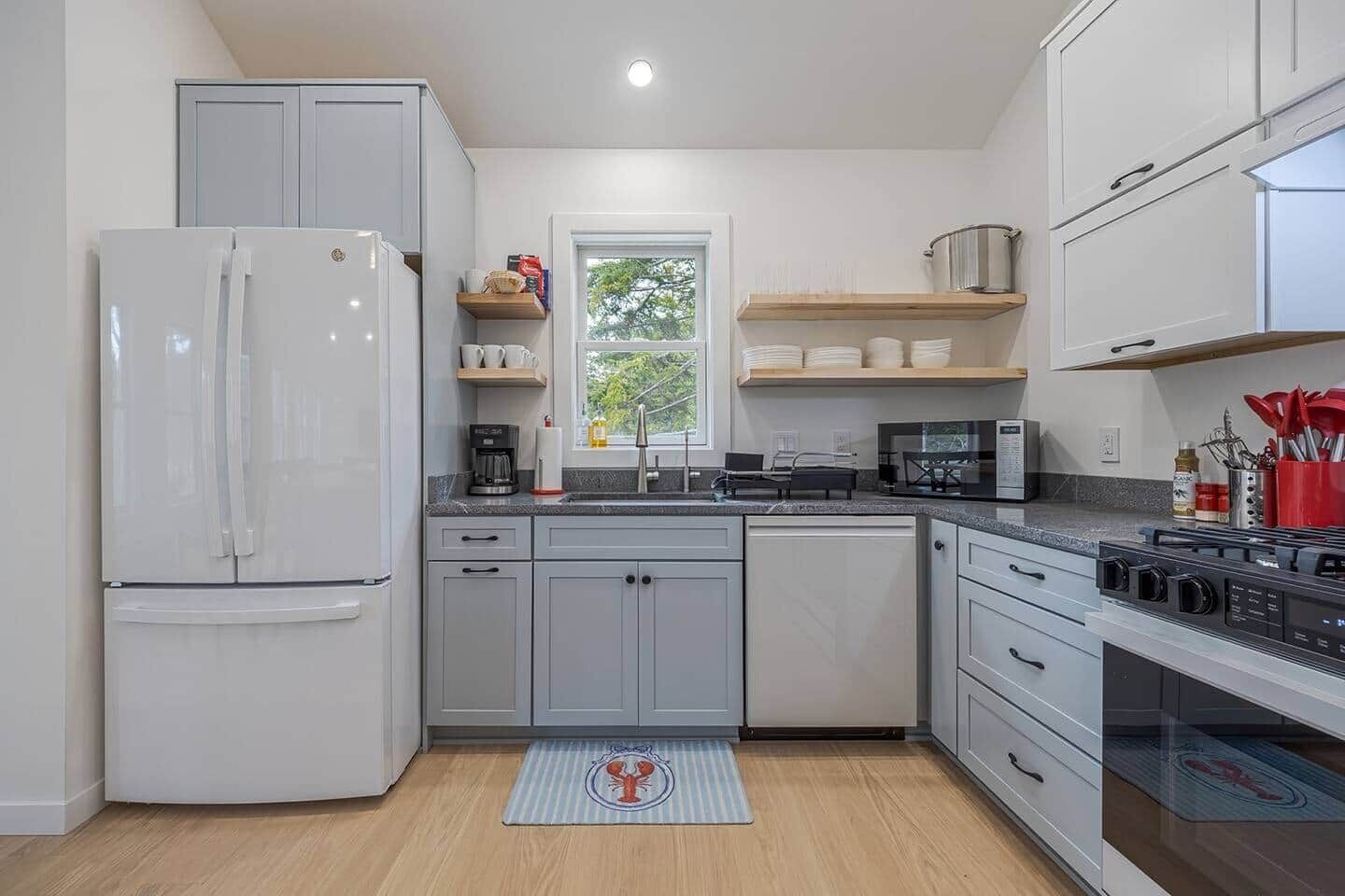 A modern kitchen with a refrigerator, microwave, stove, and wooden shelves.