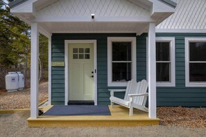 A house with a green exterior, a white porch, a door with a sign, and two white chairs. - Ecodia: Eco conscious stay near Acadia NP (Tremont)