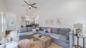 A modern living room with a grey sectional sofa, a wooden coffee table, and a ceiling fan.