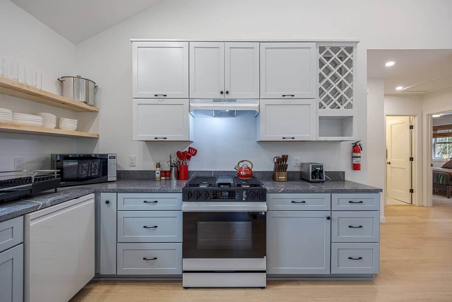 A modern kitchen with white cabinetry, a built-in oven, a gas stove, and a microwave.