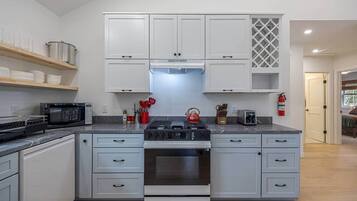 A modern kitchen with white cabinetry, a built-in oven, a gas stove, and a microwave.