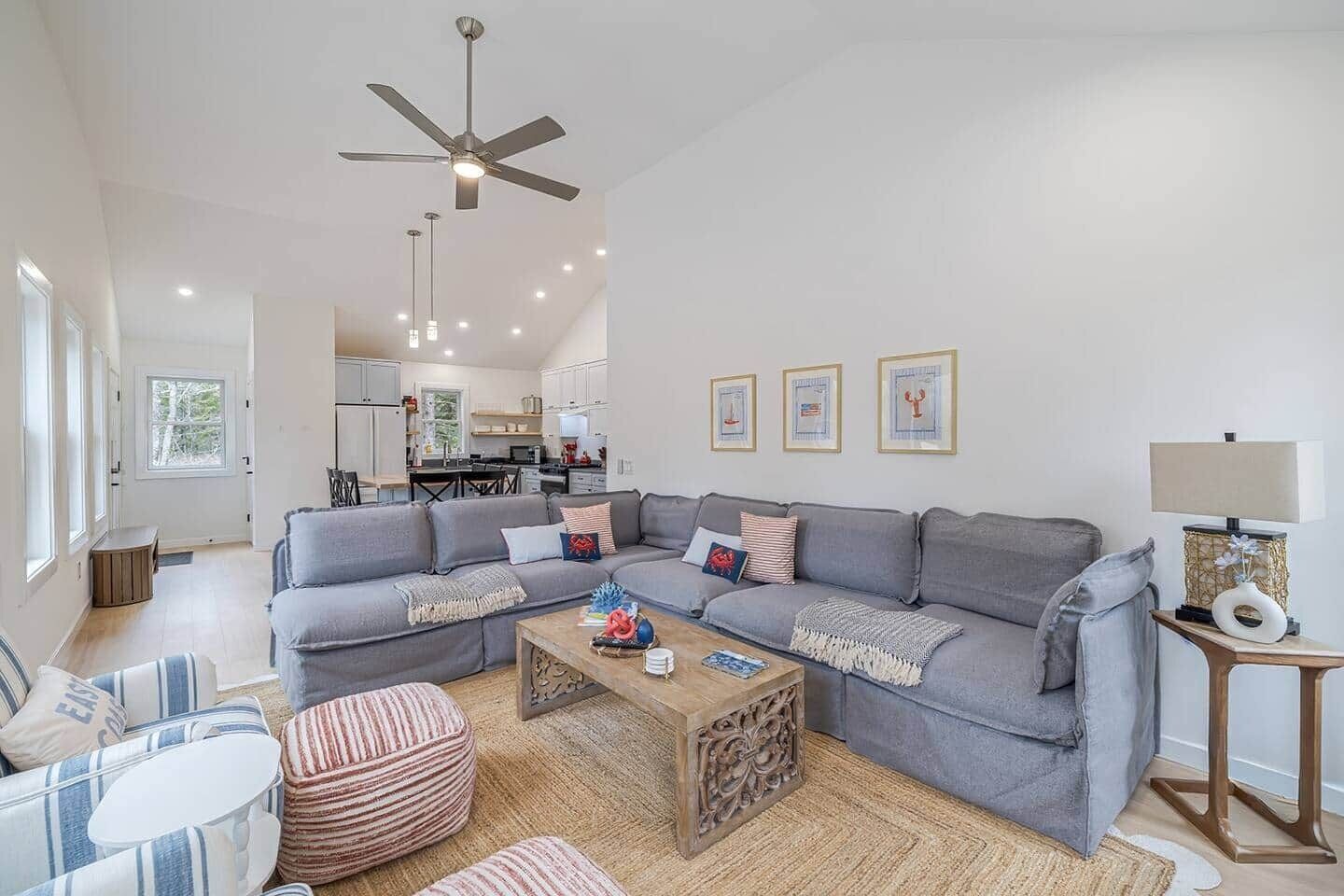 A modern living room with a grey sectional sofa, a wooden coffee table, and a ceiling fan.