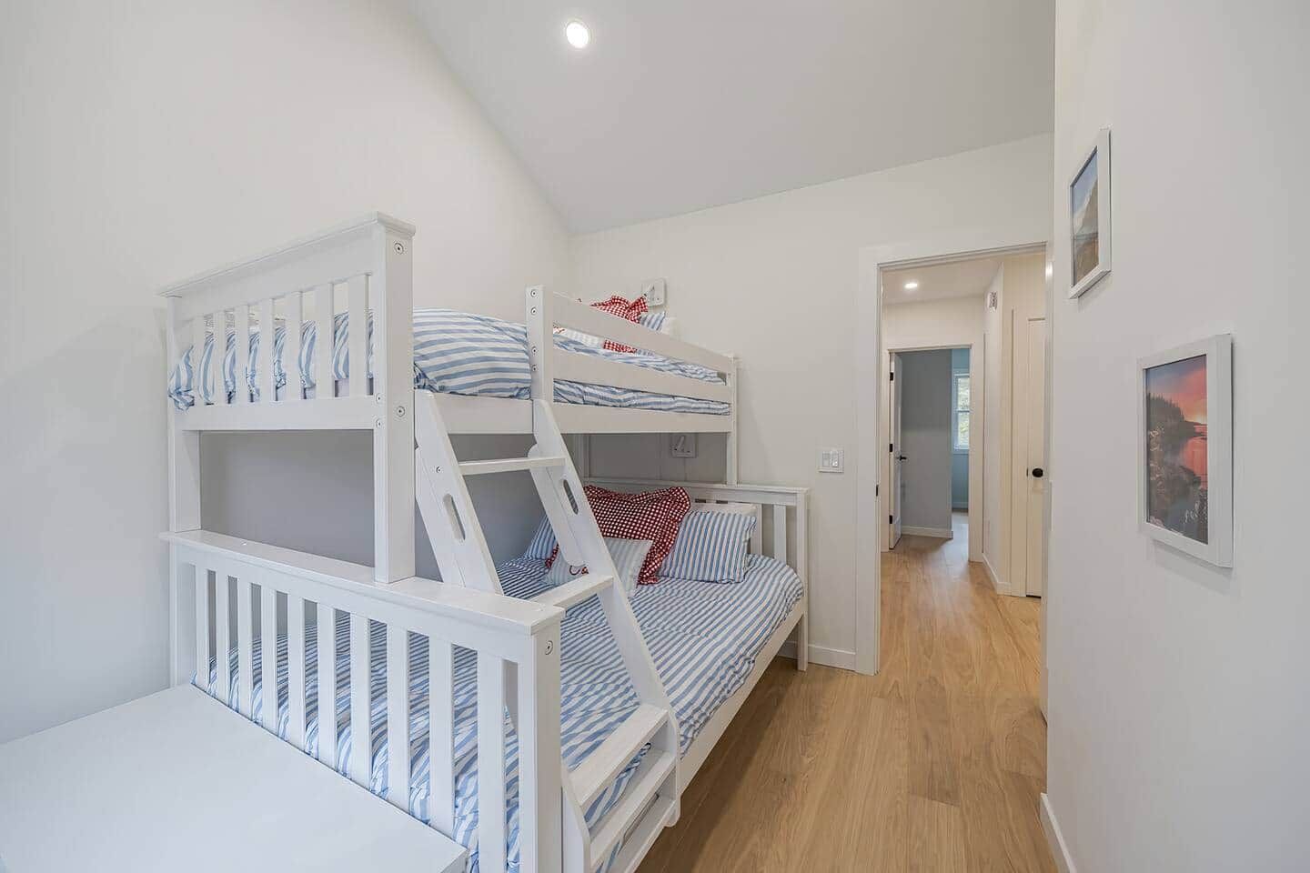 Une chambre avec des lits superposés, un couloir et une porte donnant sur une autre pièce.