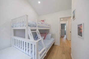 Un dormitori amb lliteres, un passadís i una porta que condueix a una altra habitació.