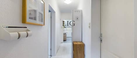 En hall med en träbänk, en inramad tavla och en vit dörr.