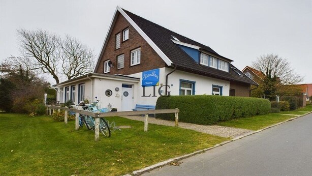 A two-story building with a sign for 'Strandhagens' and a visible entrance. - Holiday apartment Laughing Gull (Langeoog)