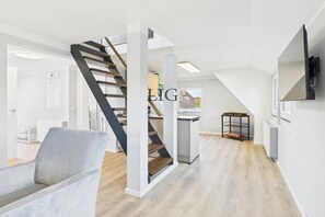 Ein modernes Interieur mit Treppe, einer Couch und einem Fernseher.