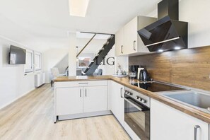 Eine moderne Küche mit weißen Schränken, einer Holz Arbeitsplatte, einem eingebauten Ofen und einer Edelstahl-Spüle.