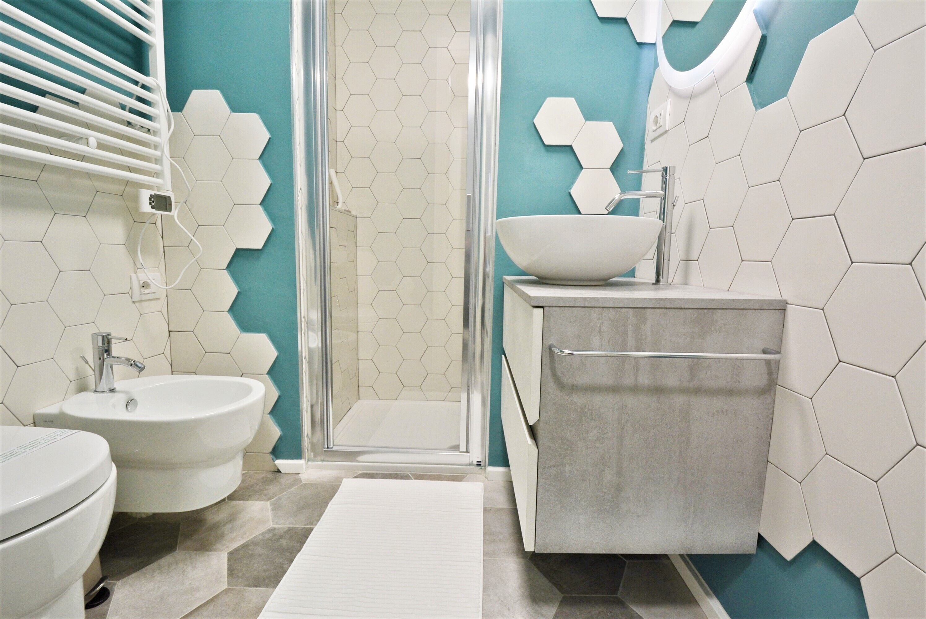A bathroom with a shower, bidet, sink, and toilet.