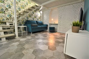 A modern interior with a staircase, a sofa, a small table, and a potted plant. - Milano Apartments Lombardini (Milano)
