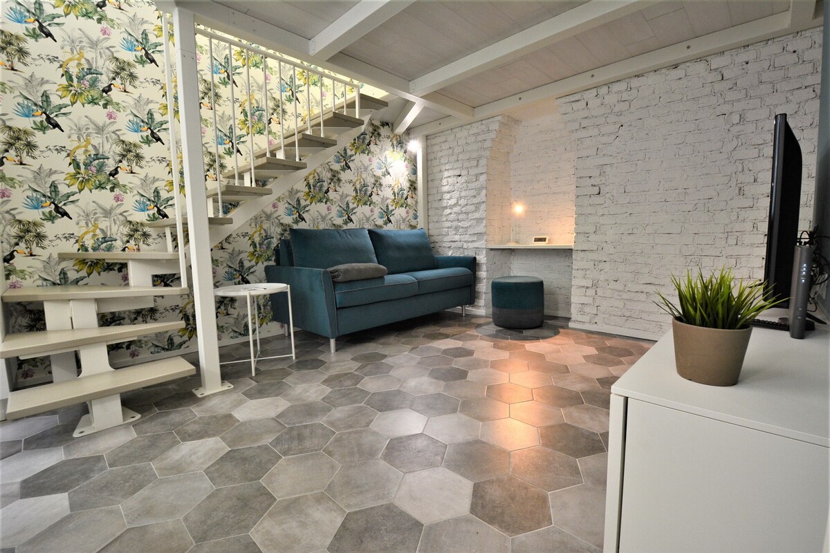 Ein modernes Wohnzimmer mit Treppe, einer Couch, einem Couchtisch und einer Topfpflanze.