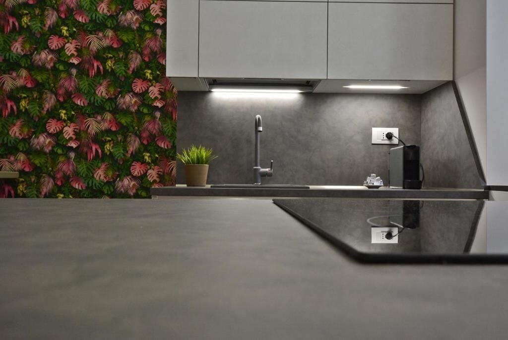 Eine moderne Küche mit grauer Arbeitsplatte, einer Edelstahlspüle und einem Blumentopf.