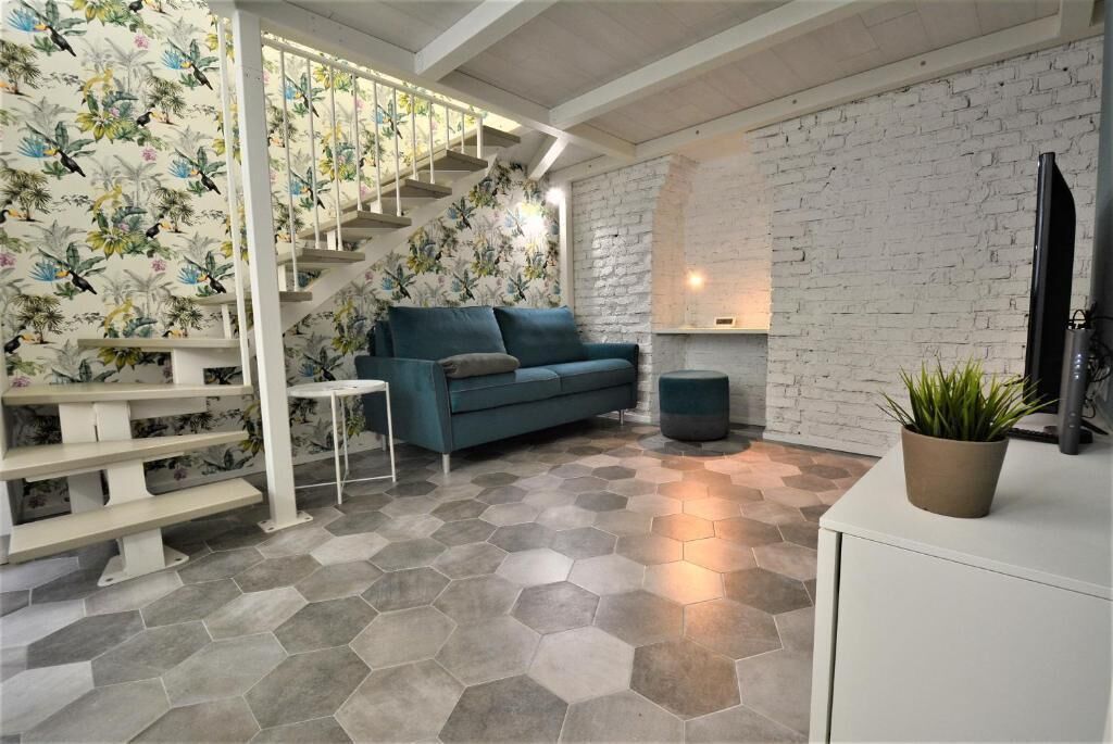 A modern living room with a staircase, a sofa, a coffee table, and a TV.