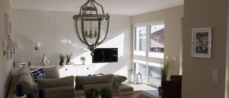 A living room with a wooden coffee table, a chandelier, a sofa, and a television.