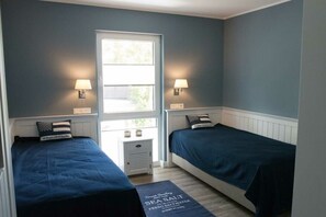 Ein Zimmer mit zwei Betten, einem Fenster und zwei Wandlampen.