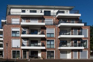 Ein mehrstöckiges Wohngebäude mit Balkonen, Garagentoren und einer Ziegel Fassade.