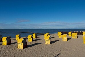 Een strand met rijen gele strandstoelen, voorzien van nummers.
