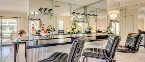 A modern kitchen with a central island, bar stools, and a large mirror.