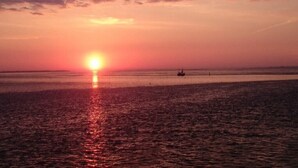 Un atardecer sobre un cuerpo de agua tranquilo, con un barco y una boya a la vista.