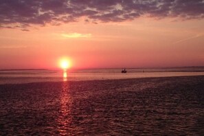 Un tramonto su una distesa d'acqua calma, con una barca e una boa visibili.