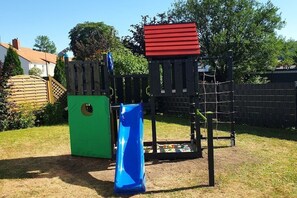 A playground with a slide, climbing net, and a red platform. - Holiday apartment with 3 bedrooms (Langelsheim)