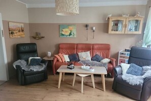 A living room with a sofa, two armchairs, a coffee table, and a cabinet with decorative items. - Holiday apartment with 3 bedrooms (Langelsheim)