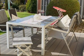An outdoor patio with a glass-top table, cushioned chairs, and a red umbrella. - Holiday apartment with 3 bedrooms (Langelsheim)