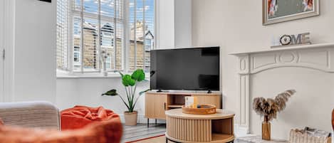 Una sala de estar moderna con televisor, chimenea y un amplio ventanal con persianas.