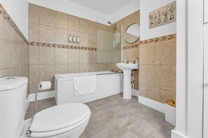 Un baño con inodoro, bañera y lavamanos.