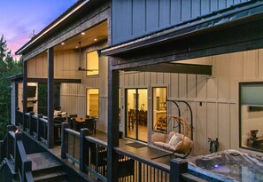 Un edificio de dos pisos con un porche cubierto que incluye mobiliario exterior y un jacuzzi.