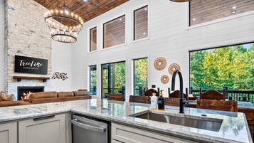 A spacious kitchen with a large island, a fireplace, and a view of the outdoors.