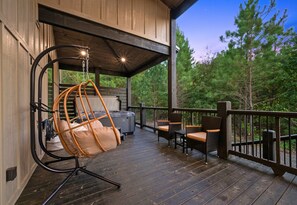 Eine Holzterrasse mit einer Hängematte, zwei Korbstühlen und einem Whirlpool.