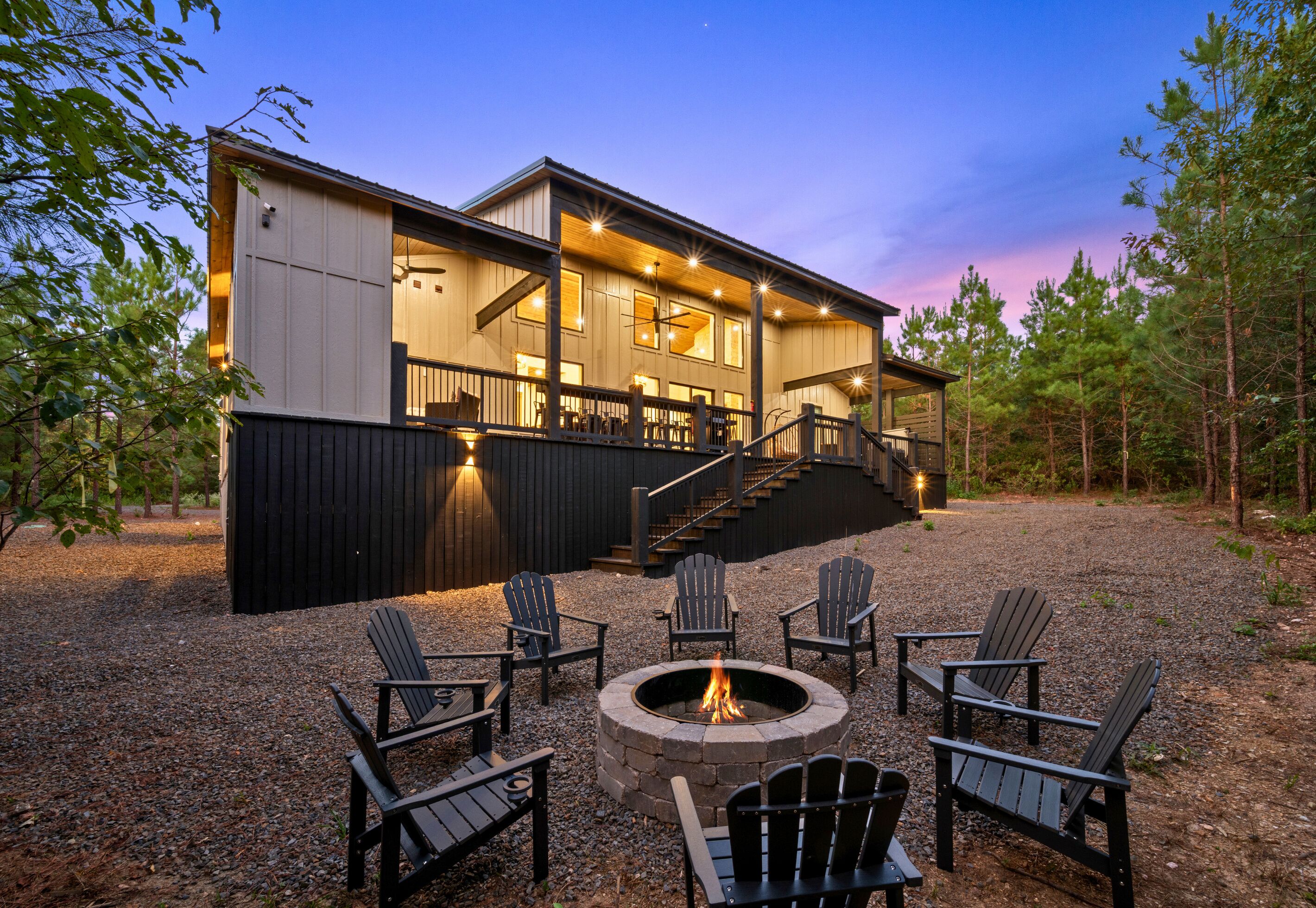 A two-story cabin with a deck, outdoor seating, and a fire pit.